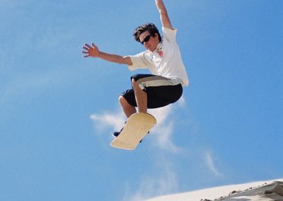 Teen male flying through the air on a sandboard.