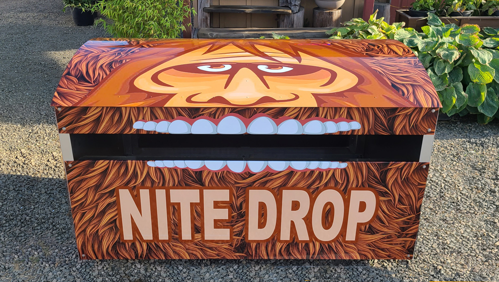 A sandboard nite drop box with an illustrated face and mouth.