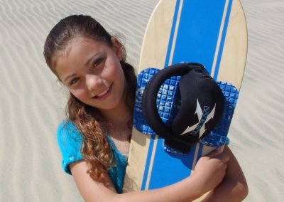 A cute young girl hugging here custom sandboard.